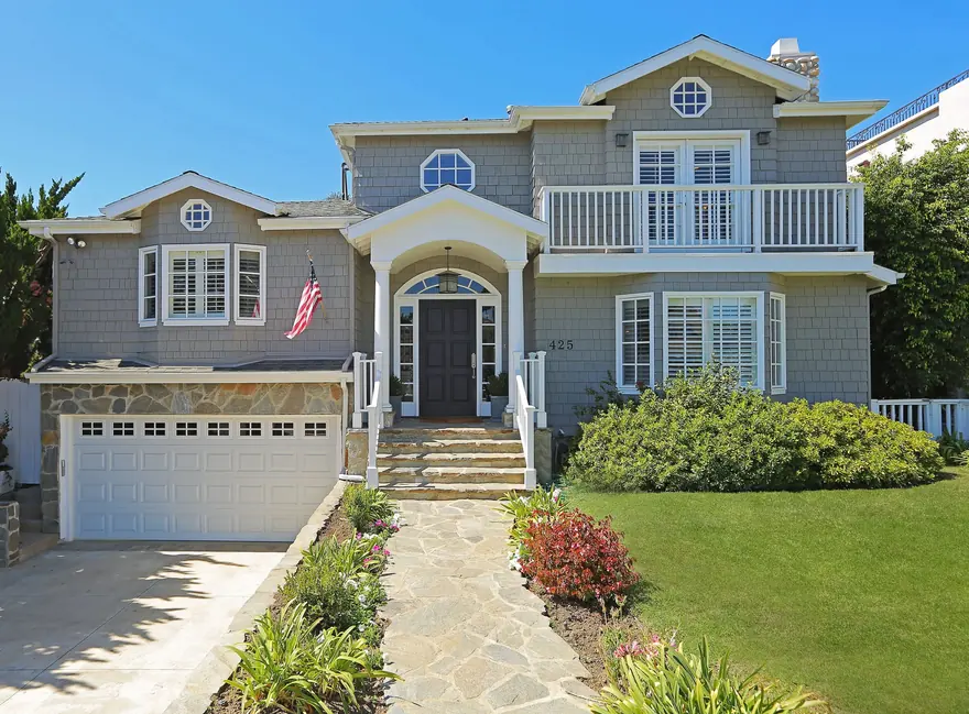 Front elevation of a grey shingled Westside home with a stone path to the entry