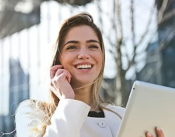 Smiling woman on a phone call holding a tablet while she gets her finances in order